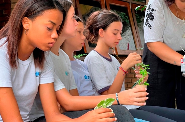 Jovens cuidando de mudas em oficina ambiental