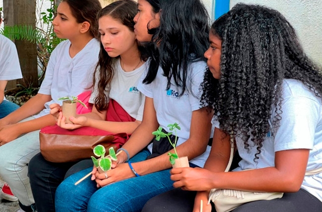 Jovens com mudas durante atividade de educação ambiental